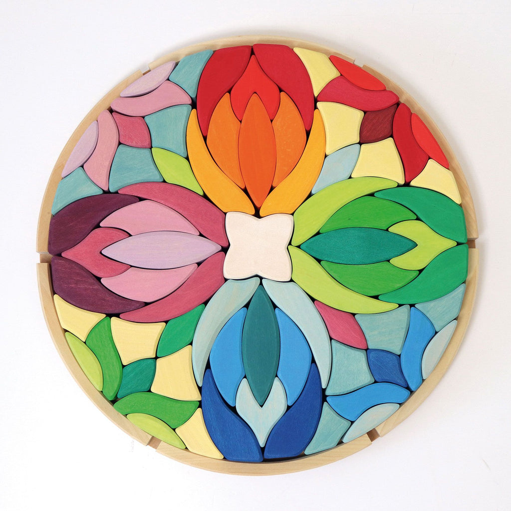 A colorful, circular wooden puzzle featuring interlocking pieces in the shape of flower petals. Named Grimm's Lara Circle Flower Building Set, the pieces are painted in various shades of red, orange, yellow, green, blue, pink, and purple. This vibrant design enhances fine motor skills and spatial thinking skills.