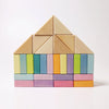 A neatly arranged set of colorful wooden building blocks from the Pastel Duo Block Set, forming the shape of a house. The blocks, resembling geometric shapes and featuring a variety of colors such as yellow, green, blue, purple, pink, and natural wood tones, are organized in a symmetrical pattern against a white background.