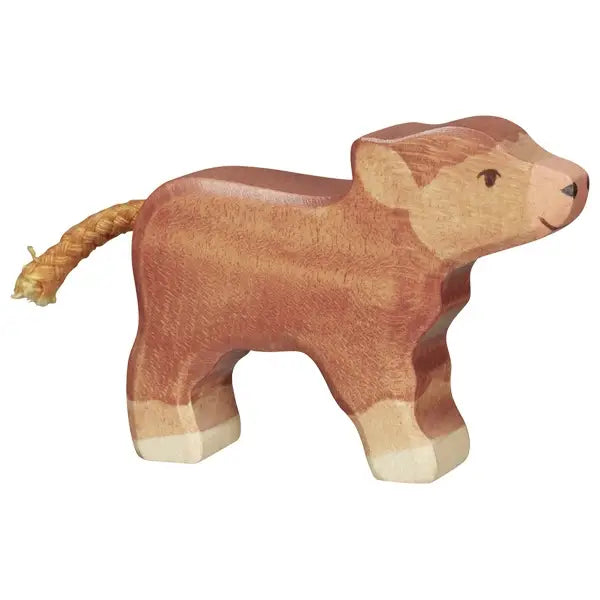 A handcrafted wooden toy calf stands on four legs. It is painted brown with lighter patches on its legs, ears, and snout. This Holztiger Highland Cattle, Small figure has a simple painted face with black eyes and a small smile, and its tail is made from braided string. Made in Europe.