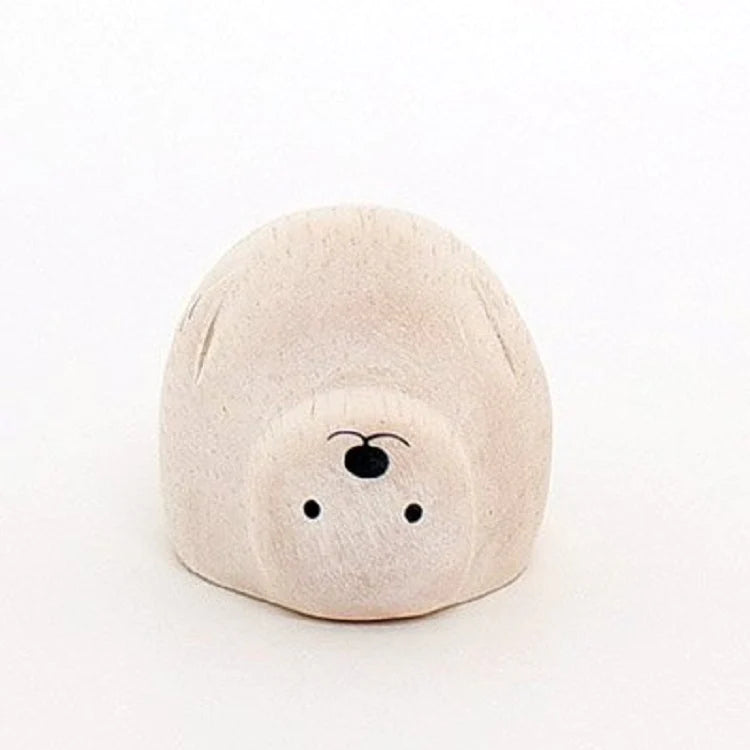 A small, rounded, beige wooden figurine of a seal with a simple, minimalist design. This one-of-a-kind decoration features black dots for eyes and nose, and subtle lines for ears and other features. It sits on a plain white background.