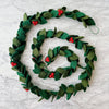 The 6' Felt Holly Garland with dark green leaves and bright red berries spirals elegantly on a white marble surface, embodying the charm of Christmas decor.