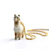 An Alpaca Necklace stands with a 24k gold chain draped over its back, resembling an alpaca necklace. The llama is intricately detailed with shades of brown and white, and the image is set against a plain white background.