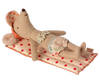 A small fabric mouse doll from Maileg Beach Float, Mouse - Red dot, lies on a polka-dotted beach mat. It is wearing a big sun hat, floral shorts, and has a lace accessory around its neck. The doll's beige-coated fabric body is stuffed and appears relaxed as if sunbathing.