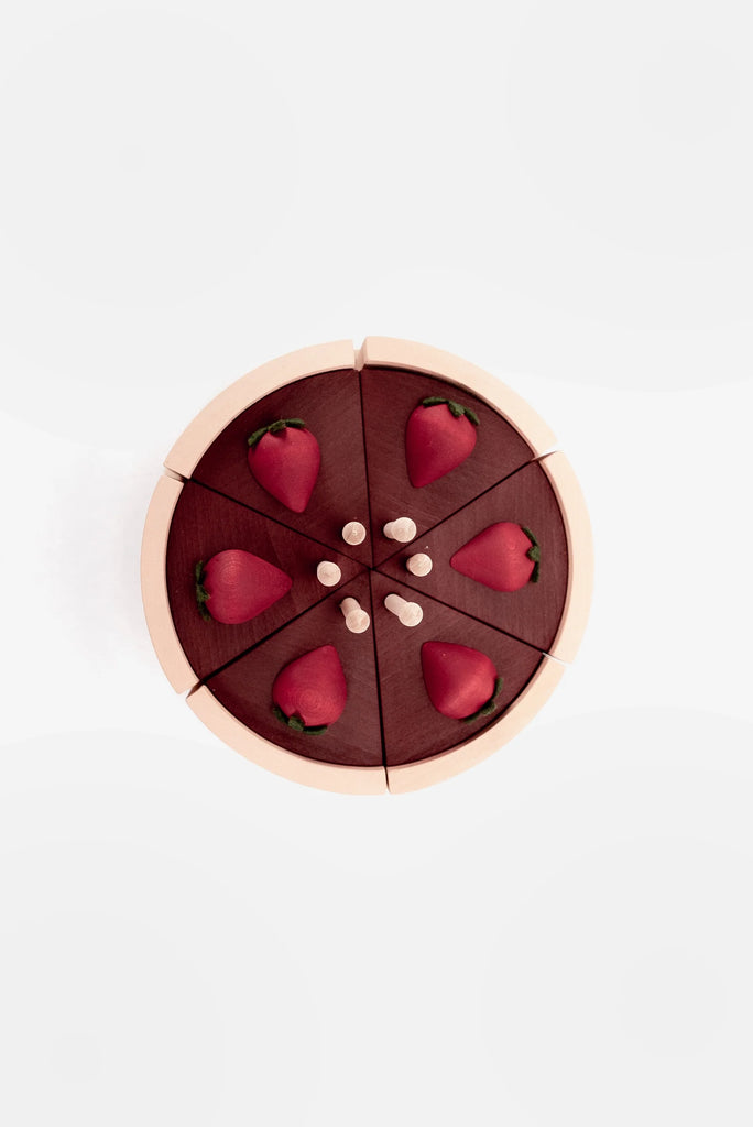 A wooden chocolate layer cake on a stand, painted with non-toxic paint, divided into six slices, each adorned with a fabric strawberry and white velcro dots, on a white background.