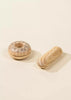 A wooden bagel decorated with black and white speckles sits next to a small wooden baguette on a beige background. These items are part of the Wooden Bakery Set, featuring simple and minimalist designs with light wood tones and smooth finishes—perfect for inspiring healthy eating habits in children's games.