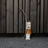 A Wooden Bow & Arrows Set with Goal made from FSC wood, leaning against a wooden fence, with arrows stored in a fabric quiver decorated with a triangle symbol.