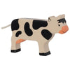 A handcrafted wooden figurine of a cow with a white body and black spots, and orange accents on the ears, nose, and udders. Made from premium maple and beech wood, this Holztiger Black Cow, Standing features a simple, painted design, a short tail, and black hooves, standing against a plain white background.