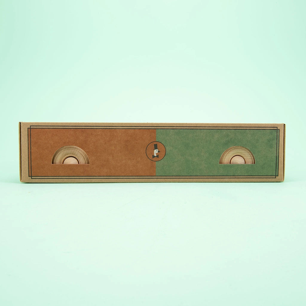 A rectangular cardboard drawer box with two compartments. The left half is brown, and the right half is green. Each side features a circular finger hole for pulling the drawers open. The Uncle Goose Classic ABC Blocks with Wagon is placed against a light green background.