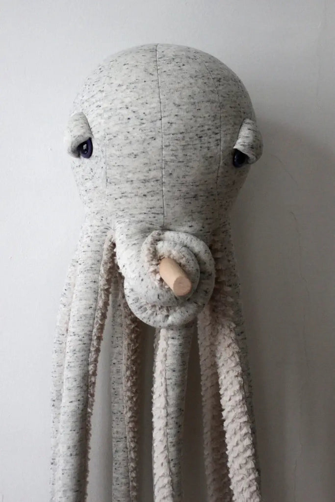 The BigStuffed Octopus - Big Original, with its gray, textured surface, is mounted against a neutral-colored wall. This plush stuffed toy features large, round eyes and multiple long tentacles extending downward, perfectly capturing the charm of the underwater world. (Ships in approximately one week)