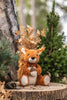 A Steiff, Phil Squirrel Stuffed Plush Animal, 8" with bushy tail sitting on a tree stump surrounded by greenery and autumn leaves in a forest setting, featuring a "Button in Ear.