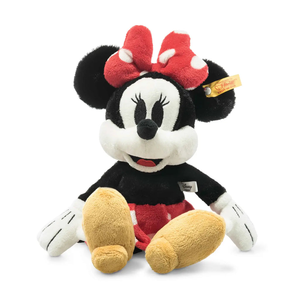 The 12-inch Steiff Disney's Minnie Mouse Stuffed Plush Toy is a delightful representation of the beloved Disney Originals character. It features large round ears, a red bow with white polka dots, white gloves, and yellow shoes. Minnie has a smiling face with long eyelashes and wears a red skirt with white polka dots. A tag is attached to her ear.