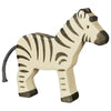 A handcrafted Holztiger Zebra is shown in this image. The zebra, part of the high-quality HOLZTIGER figures made in Europe, is painted white with black stripes, tail, snout, and hooves. The design is simplistic and cartoon-like, perfect for children. The zebra stands on all four legs.