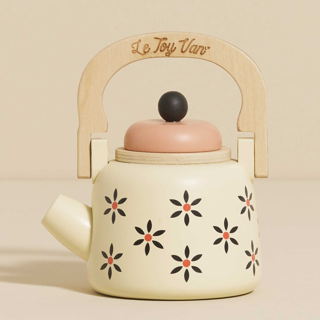 The Vintage Wooden Role Play Kettle is a cream-colored toy teapot featuring a wooden handle and lid, made from FSC certified wood. It showcases an eco-friendly design with black and red floral patterns. The engraved text on the handle adds a whimsical charm to this delightful piece.