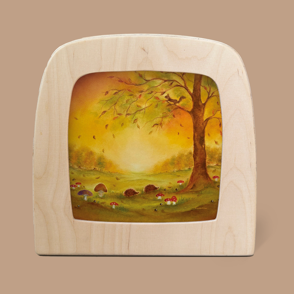 The product, "Silhouette Only - Autumn Leaves Silhouette for Toverlux Lamp," frames a captivating autumn scene with a tree shedding leaves, mushrooms, and a hedgehog on the forest floor. Its warm colors evoke a serene and natural atmosphere, while magic silhouettes enhance the enchanting display of autumn leaves.