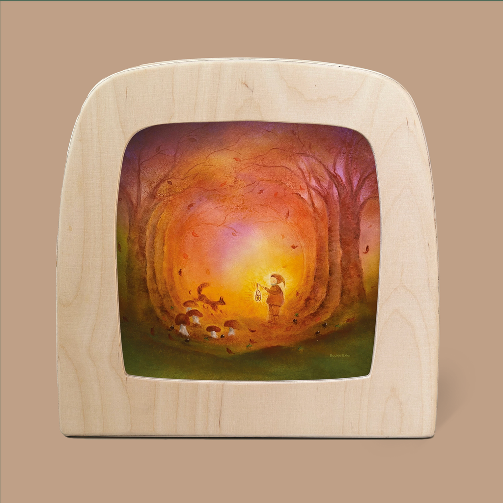 A wooden frame surrounds the "Silhouette Only - Autumn Light Silhouette for Toverlux Lamp," featuring an illustration of a serene forest scene. The enchanting shadows highlight a child holding a lantern, illuminating a path amidst tall trees with vibrant autumn leaves. Magic silhouettes of small animals, such as foxes, accompany the child, heightening the whimsical atmosphere.