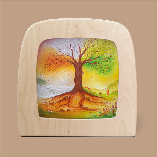 A wooden frame featuring the "Silhouette Only - Tree of Seasons for Toverlux Lamp" beautifully illustrates the magic silhouettes of the four seasons: spring, summer, autumn, and winter. Each quadrant captures distinct seasonal elements such as snow, flowers, and falling leaves, harmoniously integrated into the artwork. This product ships in approximately one week.