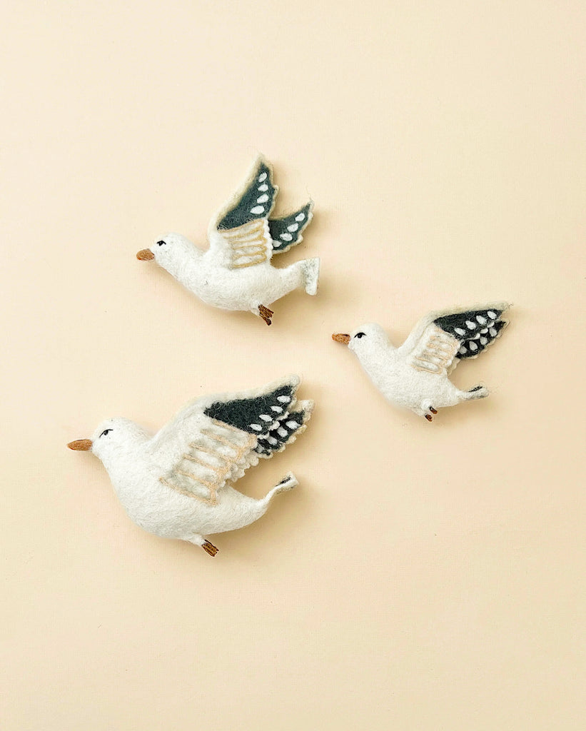 Three Flying Seagulls Wall Decor on a pale pink background, each crafted with white bodies and detailed wing patterns in darker tones.