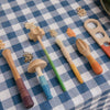 Various Grapat Tools laid out on a blue and white checkered tablecloth, surrounded by small piles of grains and legumes.