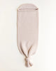 A HVID Merino Wool Cocoon - Oat is laid flat on a white background. The cylindrical bag, resembling a cozy baby cocoon, has an opening at the top and is tied in a single knot at the bottom.