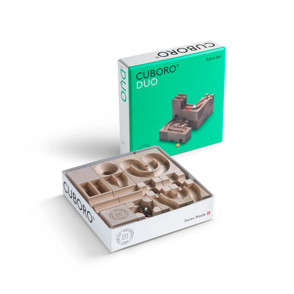 A Cuboro DUO Marble Run Extra Set. The image shows the box with various wooden pieces made from sustainable Swiss beech wood arranged neatly. The lid, propped up behind, displays the brand name "Cuboro DUO Marble Run Extra Set" and an image of an assembled marble run. The set is labeled as "Swiss Made.