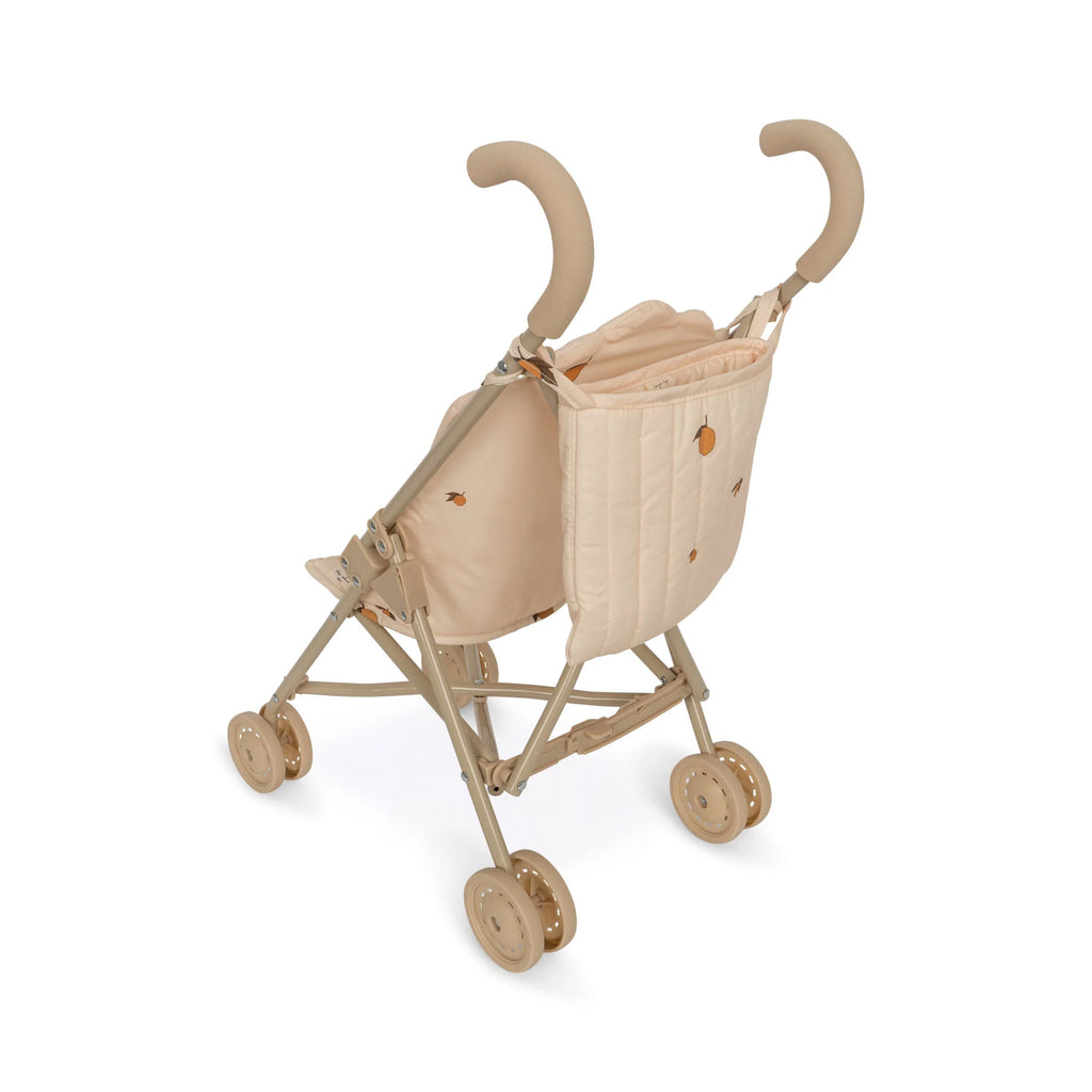 A beige, foldable Konges Sloejd Doll Stroller - Lemon with cushioned handles and double wheels. The fabric seat is adorned with a minimal design and features a secure harness. The stroller frame is made of light-colored metal, perfect for carrying dolls or stuffed animals.