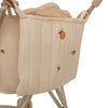 A close-up of a beige Konges Sloejd Doll Stroller - Lemon with a quilted fabric cover featuring small orange fruit patterns. The stroller's metal frame is visible, and the removable fabric appears padded for comfort. The double wheels ensure stability during play.