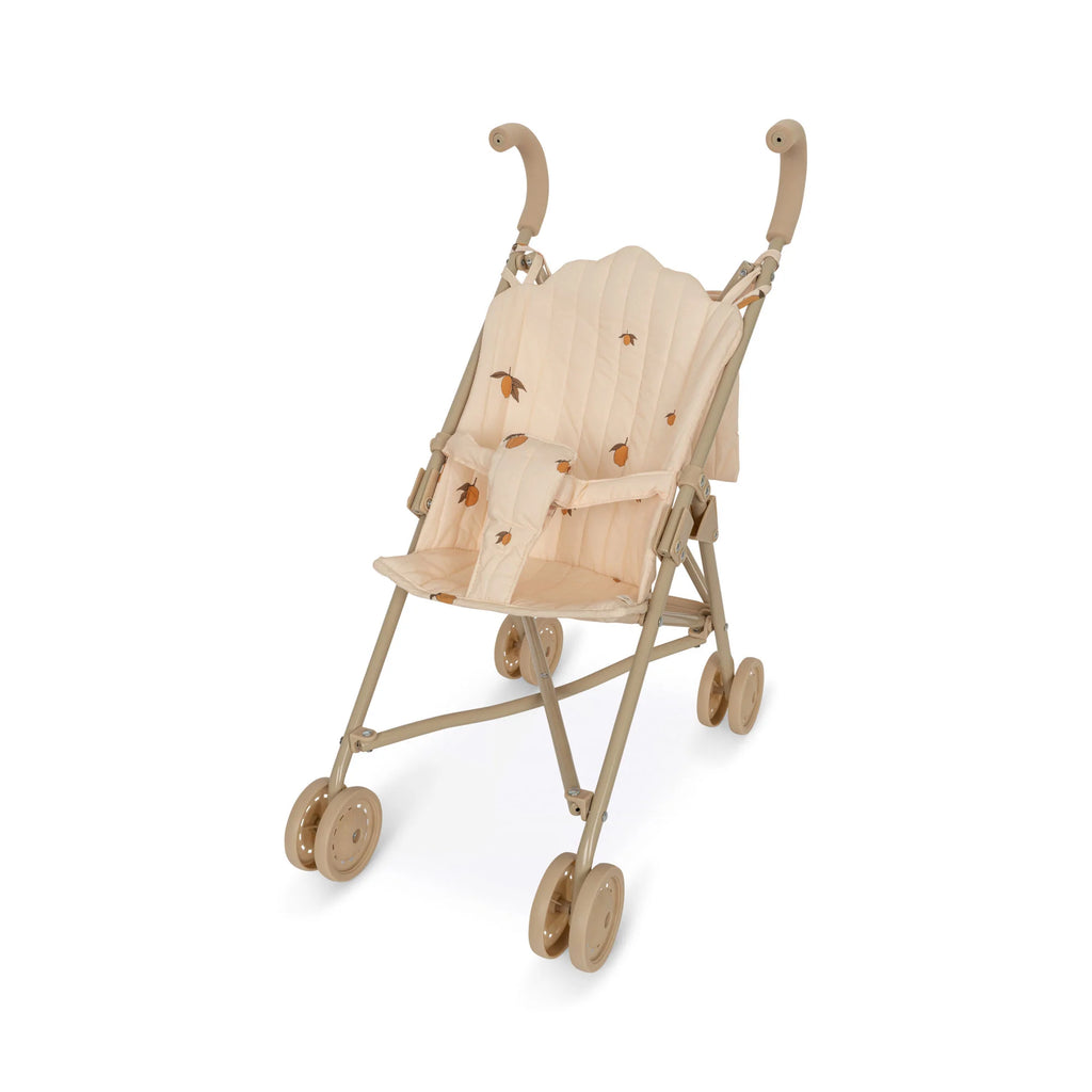 A light brown Konges Sloejd Doll Stroller - Lemon with a simple frame and four double wheels. The fabric seat is beige with small, printed designs of flowers and leaves. The stroller features curved handles for easy pushing and a secure harness to keep your little one safe.