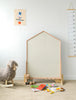 A children's playroom showcases the impressive NORITER Signature Double-Sided Board Bundle, designed perfectly for educational play. Adding charm to the room is a delightful rocking sheep toy and a cuddly teddy bear, while magnetic alphabet pieces are strewn among books and colored pencils. A vibrant drawing adorns the wall alongside a convenient height measurement chart.