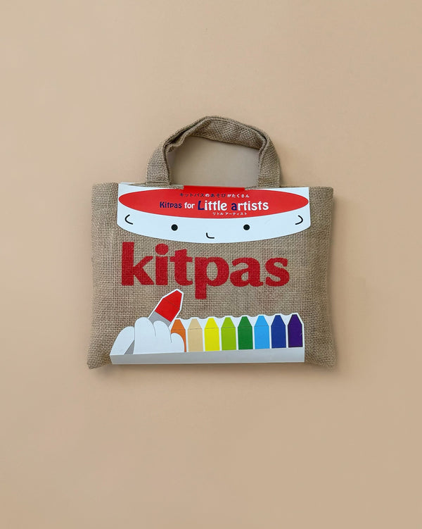 A jute bag titled "Kitpas Creative Crayon Bag for Little Artists" features vibrant crayon illustrations at the bottom, inviting imaginative painting adventures. Handmade by craftswomen, it stands out against a soft light beige background.