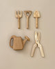 A set of five Handmade Pretend Play Gardening Tools displayed on a beige surface. The playset features a pitchfork, a rake, a hand spade, a watering can, and a pair of pruners. Each tool is meticulously crafted from light-colored wood, boasting a simple design and smooth finish.