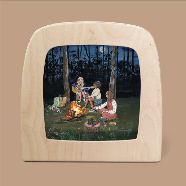 Framed in a wooden, TV-shaped border, the "Silhouette Only - Campfire Nights for Toverlux Lamp" depicts three magical figures gathered around a campfire in a nighttime forest. One person strums a guitar while the others listen attentively, their silhouettes illuminated by the dancing flames. Nearby, baskets and a lantern complete the cozy atmosphere.