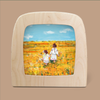 A painted image in a wooden frame showcases two children dressed in white attire walking through a vibrant yellow field beneath a blue sky dotted with clouds, evoking the unique atmosphere of the Silhouette Only - Sisters for Toverlux Lamp.