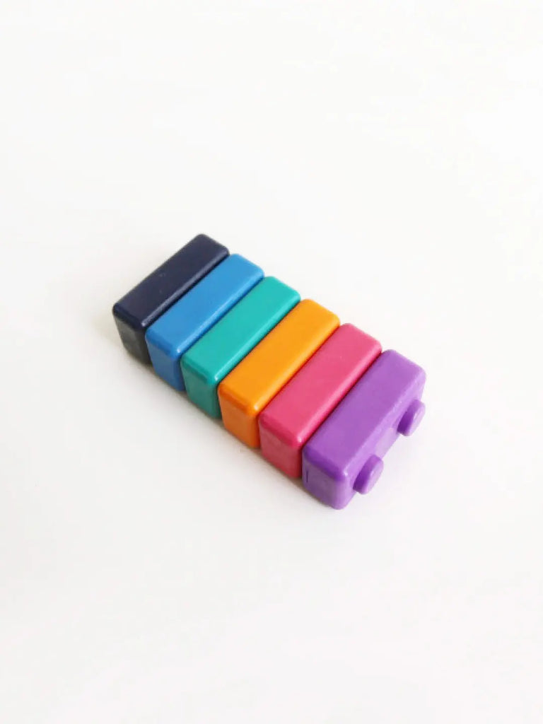 A small toy Jumbo Block Crayons with six colorful bars, arranged from dark blue to purple. Designed to resemble a miniature version of the musical instrument, it encourages fine motor skill development. The vibrant colors are akin to those found in jumbo block crayons, ensuring a playful learning experience.