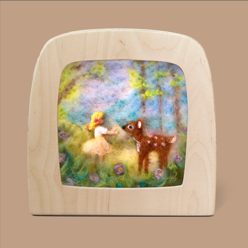 The enchanting "Silhouette Only - Girl with Deer for Toverlux Lamp" artwork features a captivating felted wool depiction of a girl in a yellow hat and dress, reaching out toward deer amidst trees and purple flowers, all set against a soft, colorful background in a wooden frame.