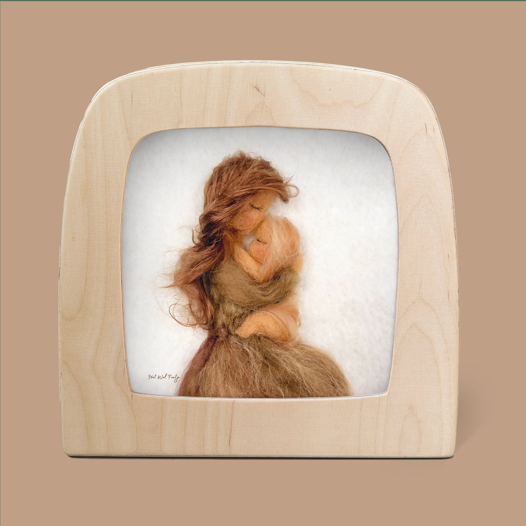 The "Silhouette Only - Mother love for Toverlux Lamp" features a felt artwork of a mother embracing her child, elegantly showcased in a wooden frame set against a soft brown background. Crafted with Magic Silhouettes, the figures are composed of natural fibers in shades of brown and beige, imbuing the piece with an ethereal beauty.