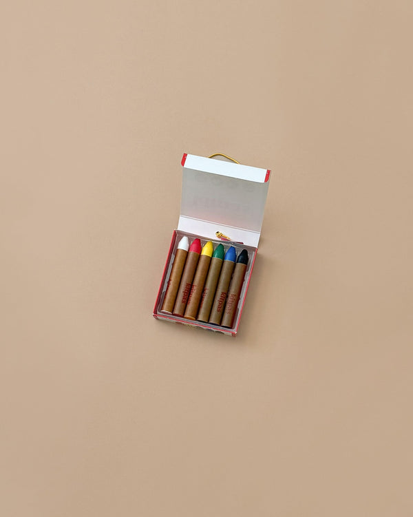 A small, open set of Kitpas Crayons - 6 Colors is neatly lined up on a neutral background. These non-toxic, vibrant crayons are wrapped in brown paper and come in red, yellow, white, pink, blue, and brown hues, making them ideal for watercolor painting.