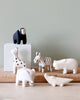 Handmade Tiny Wooden Safari Animals set, featuring an alligator along with a black and white monkey, a giraffe with black spots, a zebra, a hippopotamus, and an elephant, are displayed on the table. These minimalistic and charming hand-painted figurines have a natural Albizia wood finish with detailed paintwork.