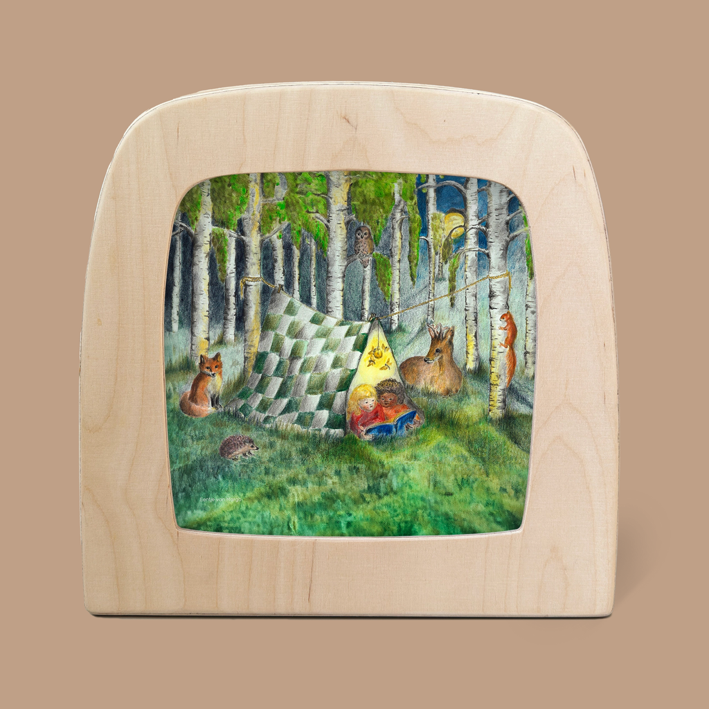 A whimsical watercolor painting in a wooden frame shows animals such as a fox, rabbit, deer, and owl gathered around the Forest Whispers Silhouette. They are assembled near a quilt tent in a forest clearing, where a cat rests cozily under the translucent fabric with colorful pillows and an illuminated Toverlux lamp.