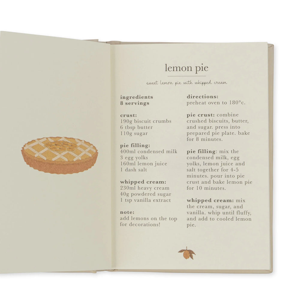 Open recipe book showing a recipe for lemon pie. The recipe includes an image of a pie with crisscrossed crust, perfect for tiny bakers. The page lists ingredients and directions for the pie crust, pie filling, and whipped cream, along with an optional garnish of lemon zest to complete your Madeline Baking Set - Petite Cousine.