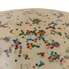 A close-up of a round, smooth, beige object sprinkled with small, colorful heart-shaped confetti. The confetti is scattered randomly, featuring vibrant colors such as red, blue, green, yellow, and orange—similar to the playful decor you'd find in an Inflatable Mini Pool - Transparent Confetti Hearts made from durable PVC.