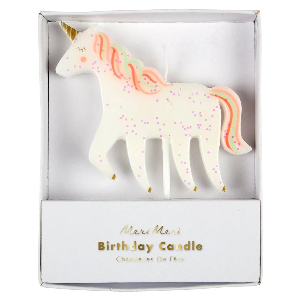 A glittering Meri Meri Unicorn Glitter Candle with pink and orange mane details, packaged in a white box labeled "meri meri birthday candle." The unicorn features a gold horn and colorful speckles.