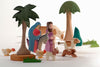 The Ostheimer Mary on Donkey set, crafted from sustainable materials, depicts Mary riding a donkey led by Joseph. They are surrounded by various animals including a cow, a goat, chickens, and a dog. The scene also features several trees and grass patches, capturing the charming style of Ostheimer toys.