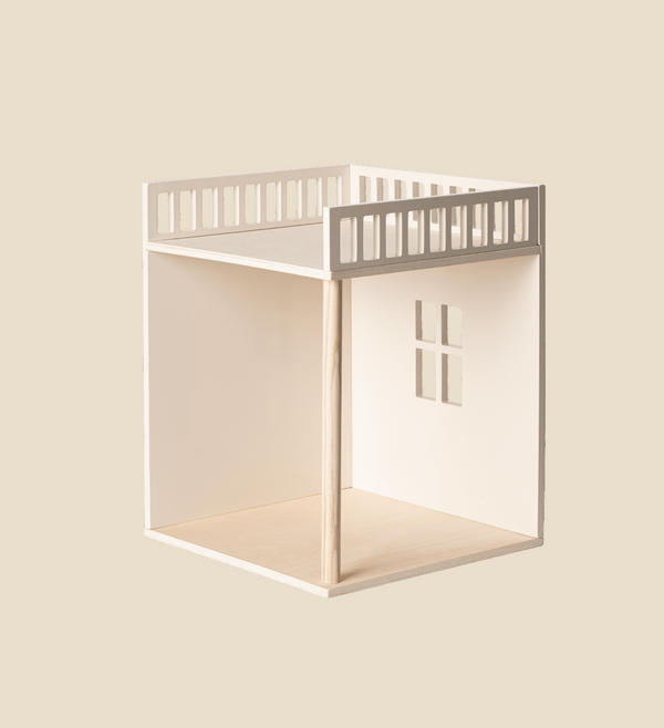 The Maileg House of Miniature Bonus Room - Bedroom, a minimalist, two-story dollhouse made of light-colored wood on a beige background. The bottom story, where wood assembly is required, features an open window cutout on one side. The top story includes a bonus room and an open rooftop area surrounded by a railing.