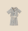 A neatly arranged striped pajama set designed for Teddy Junior, named "Maileg Extra Clothing: Pyjamas for Teddy Junior," consists of a button-up short-sleeved shirt and matching shorts. The outfit, which is available for purchase separately, features pastel blue and beige stripes on a beige background, perfect for a cozy night in with Teddy Junior.