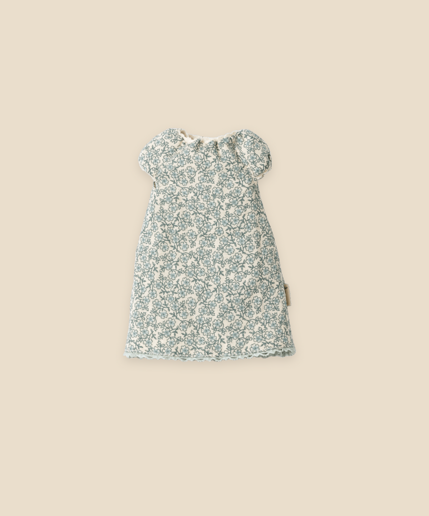 A small, patterned baby dress with short sleeves is displayed on a plain beige background. The outfit features a blue and white floral design and appears to be made of lightweight fabric. A matching Maileg Extra Clothing: Nightgown for Teddy Mum can be purchased separately to complete the adorable look.