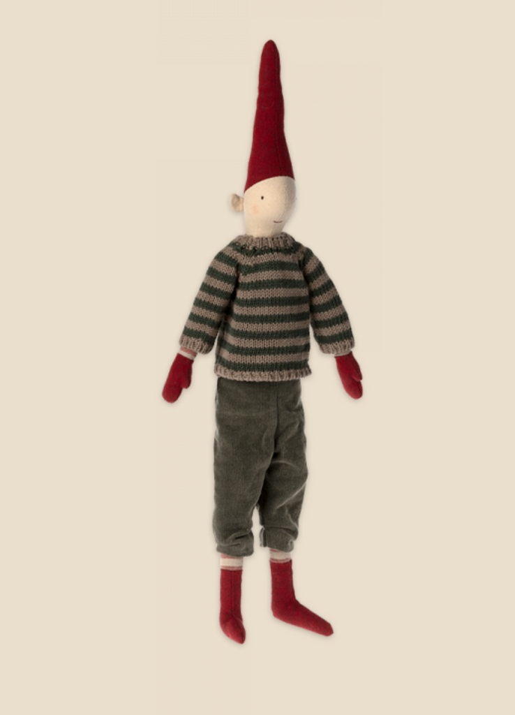 The Maileg Christmas Pixy (Size 3) features a soft toy doll dressed in a striped sweater, dark pants, red gloves, and red socks. The doll is adorned with an elongated, pointy red hat and crafted from exclusive materials, making it perfect as a Christmas decoration. With its simplistic stitched face, the Maileg Christmas Pixy stands upright against a plain beige background.