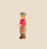 An Ostheimer Son, Gray Hat wooden toy figure with simplistic features stands against a beige background. It has blonde hair, a light gray hat, a red shirt, light brown pants, and brown shoes. Perfect for imaginative play, the handcrafted figure has a neutral expression and faces slightly to the right.