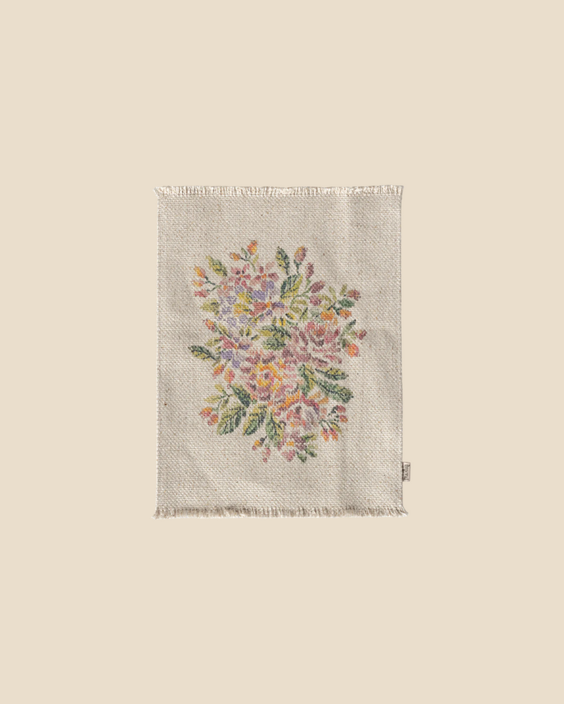 A beige cloth napkin with fringed edges is adorned with an intricately embroidered design of colorful flowers and lush green leaves, evoking the elegant Maileg Flower Rug, Large.