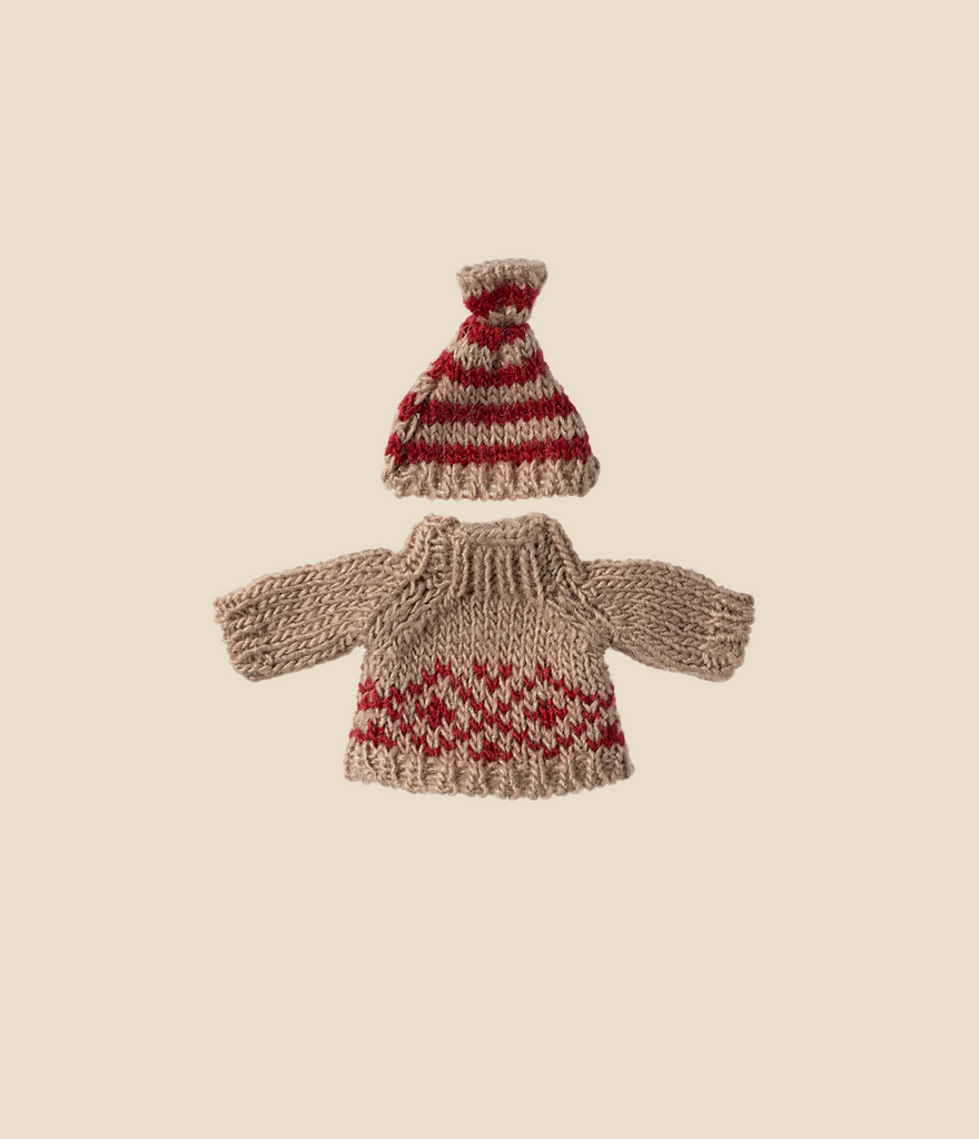 Introducing the Maileg Knitted Sweater and Hat for Mom Mouse, a delightful set perfect for wintertime. The sweater features a light brown hue with red zigzag patterns across the chest and hem, perfectly paired with a matching red hat adorned with light brown stripes and brim. Both pieces are elegantly displayed on a plain background, making them an enchanting addition to your collection. (Ships in approximately one week)