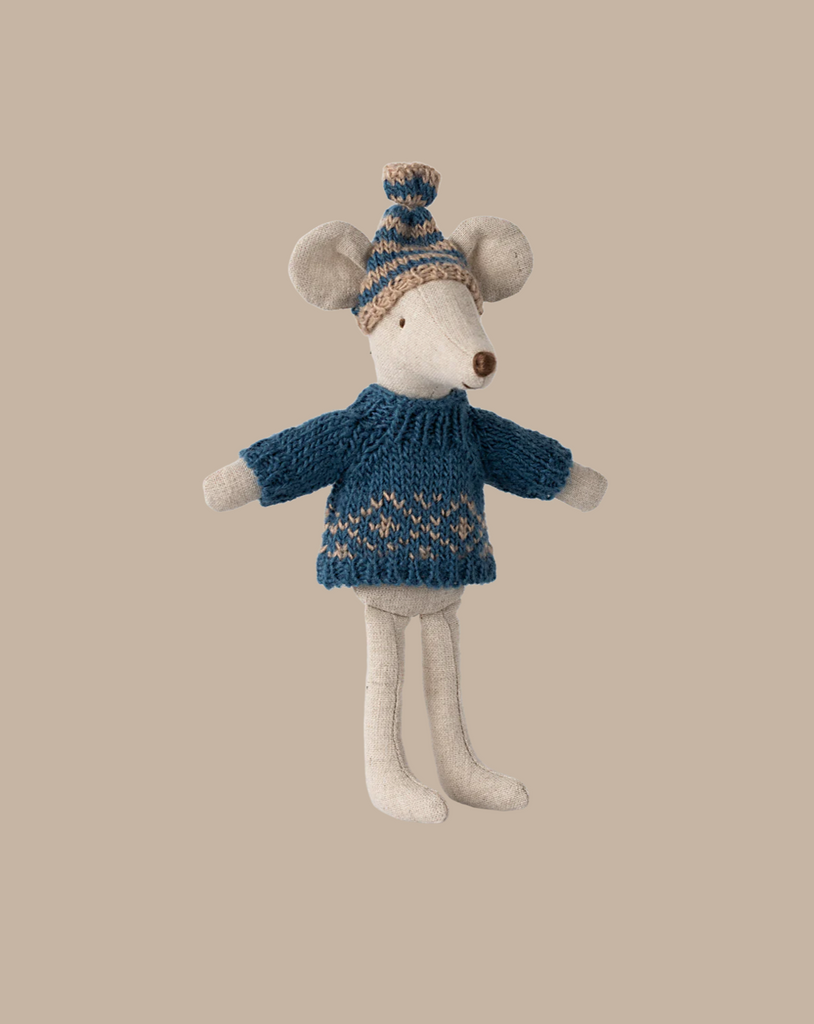 Introducing the Maileg Knitted Sweater and Hat for Dad Mouse: a plush toy mouse elegantly dressed in a blue knitted sweater featuring a charming Scandinavian pattern, complemented by a matching beanie topped with a pom-pom. Set against a solid beige background, it evokes cozy wintertime vibes.